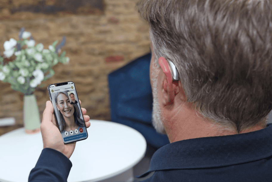 man with hearing aid holding phone