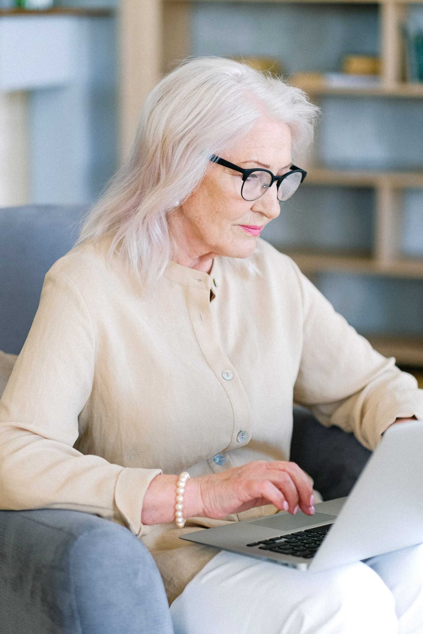 Senior woman researching hearing aids on a laptop