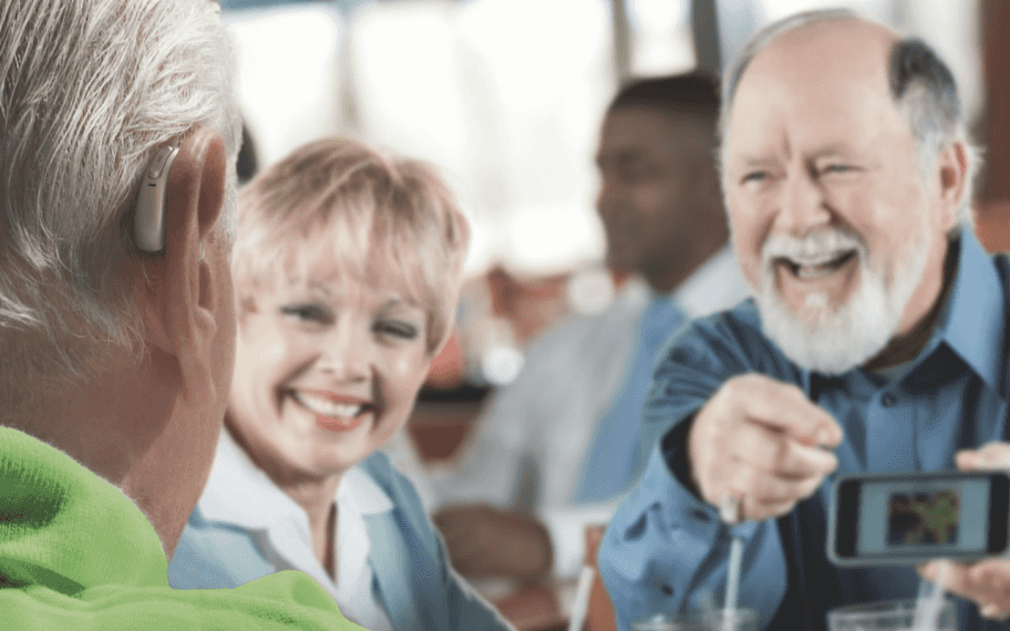 man green shirt hearing aid talking to friends